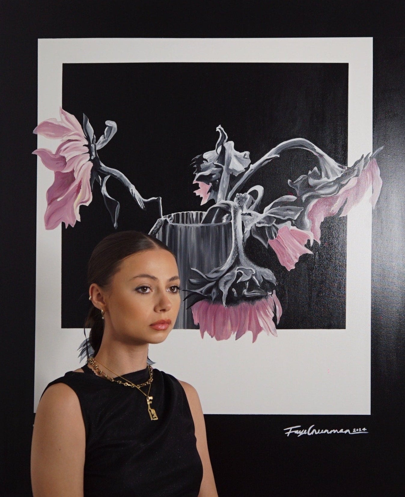 Woman standing in front of a framed artwork of pink flowers and a vase.