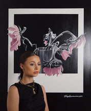 Woman standing in front of a framed artwork of pink flowers and a vase.